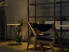 two chairs and a table in a room with metal shelving on the wall behind them