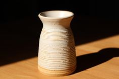 a white vase sitting on top of a wooden table