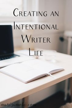 a laptop computer sitting on top of a white desk next to a book and pen