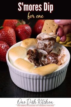 a person dipping some food into a bowl with strawberries in the backgroud