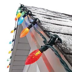 christmas lights are hanging from the roof of a house with snow on it's shingles