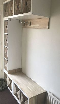 an empty room with some shelves and baskets on the wall next to a radiator