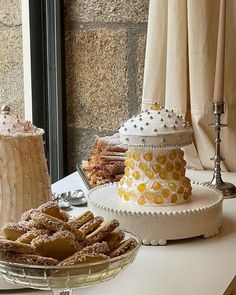 a table topped with cakes and desserts next to a window