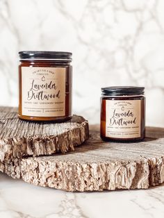 two jars of jam sitting on top of a piece of wood next to each other