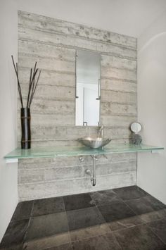 a bathroom with a glass counter top next to a sink and vase on the wall