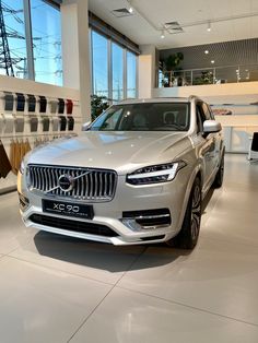 an suv is parked in a showroom with large windows and white tile flooring