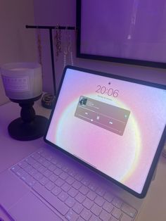 an open laptop computer sitting on top of a white desk next to a purple light