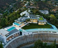 an aerial view of a large house surrounded by trees and hills in the distance is shown