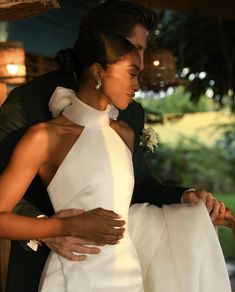 a man in a tuxedo is holding a woman's dress while they both look at each other