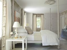 a white bed sitting in a bedroom next to two tables with lamps on top of them