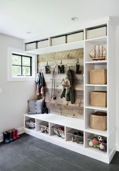 a white bookcase filled with lots of books next to a wall mounted coat rack