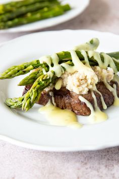 steak with asparagus and mashed potatoes on a white plate topped with gravy