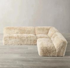 a large white sectional couch sitting on top of a wooden floor next to a wall