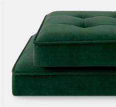 a green couch and ottoman sitting next to each other on a white surface with one foot resting on the cushion