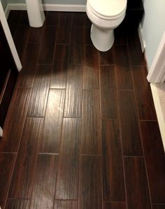 a white toilet sitting in a bathroom next to a wooden floor