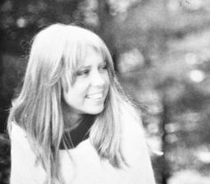 a black and white photo of a woman in the woods with long hair, smiling