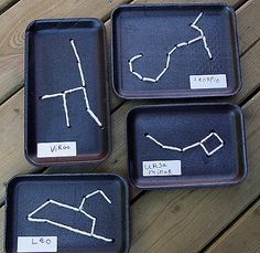 four black trays with drawings on them sitting on a wooden table next to each other