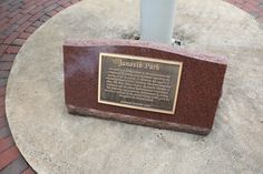 a plaque is placed on the ground in front of a lamp post and brick walkway