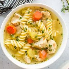 a bowl of chicken noodle soup with carrots and parsley on the side