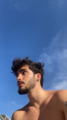 a man with no shirt on standing under a blue sky