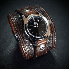 "Crafted from exquisite vegetable-tanned leather, this vintage brown cuff watch showcases a rich western saddle brown dye.  The width measures 2.5\" at its broadest, gently narrowing towards the underside of your wrist.  Artfully hand-stamped with a western border, it exudes an authentic charm.  At its pinnacle rests an exceptional water-resistant FM watch. This timepiece boasts a 316L stainless steel case, a durable sapphire crystal, and a highly reliable super Miyota quartz movement. To ensure Adjustable Steampunk Brown Watch, Mens Wrist Watches, Retro Western, Cuff Watch, Western Saddle, Saddle Brown, Vintage Cowboy, Dec 7, Tooled Leather