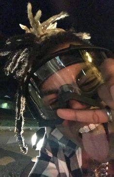 a man with dreadlocks and goggles holding something in his hand while wearing a helmet