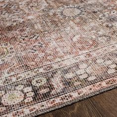 an area rug on top of a wooden floor with a brown and pink color scheme