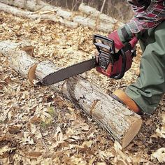 a person with a chainsaw on their feet in the leaves next to a log