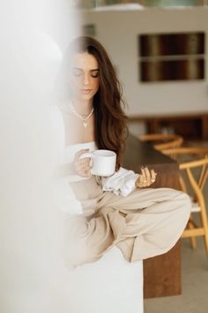 a woman holding a coffee cup and looking at her cell phone