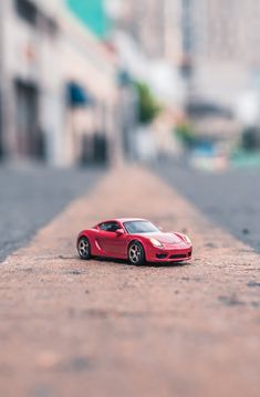 a red toy car sitting on the side of a road