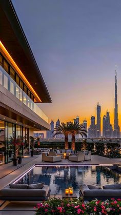 an outdoor swimming pool in front of a cityscape at dusk with the sun setting