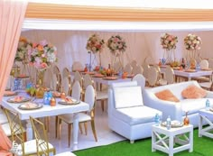 a room filled with lots of white furniture and flowers on the wall above it is a banquet set up