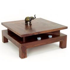 an elephant figurine sitting on top of a wooden coffee table with two candles