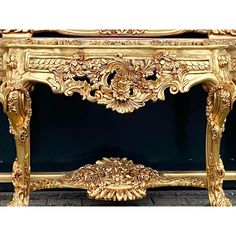 an ornately decorated gold console table with black glass doors and carvings on the sides