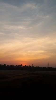 the sun is setting over an open field