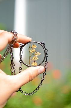 a hand holding a magnifying glass with a plant in the reflection on it