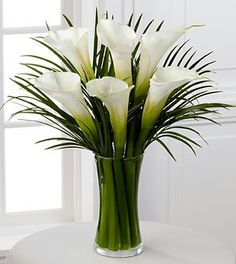 white flowers are in a clear vase on a table