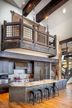 a kitchen with wooden floors and an island in front of the stove top oven, surrounded by stools