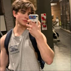 a young man taking a selfie with his cell phone in an indoor gym area