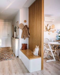 a cat sitting on top of a wooden bench in a living room next to a table