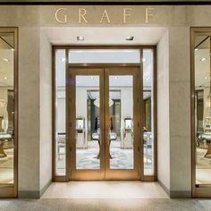 an entrance to a store with glass doors and gold lettering on the front door that says graff