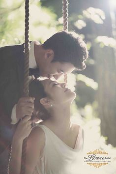 a man and woman are kissing on a swing