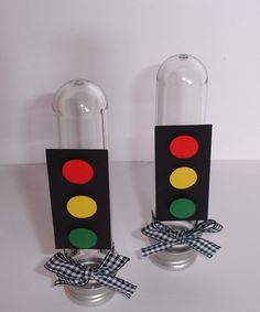 two traffic lights are sitting next to each other on a white surface with black and red ribbons