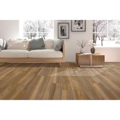 a living room with wood flooring and pictures on the wall above the white couch