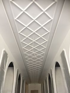 an empty hallway with white walls and ceiling tiles