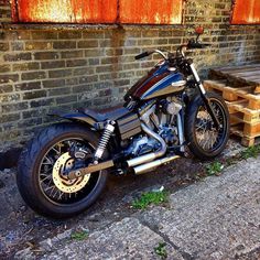 a motorcycle parked next to a brick wall and some wooden pallets on the ground