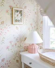 a baby's room with floral wallpaper and a basket on the table next to it