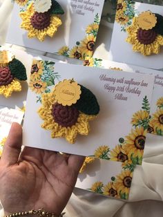 a person holding up some cards with crocheted flowers on them in front of sunflowers