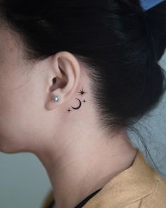 a woman's ear has a small star and moon tattoo on it