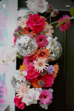 flowers and disco balls hanging from the side of a door